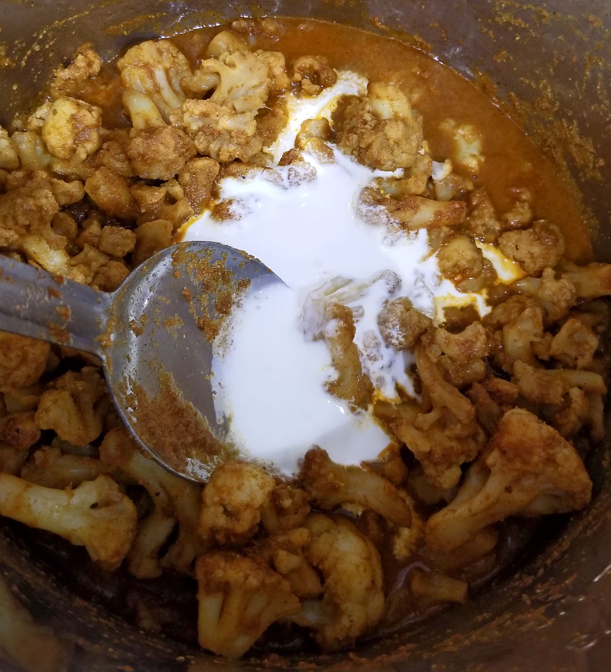 adding cream to cauliflower curry