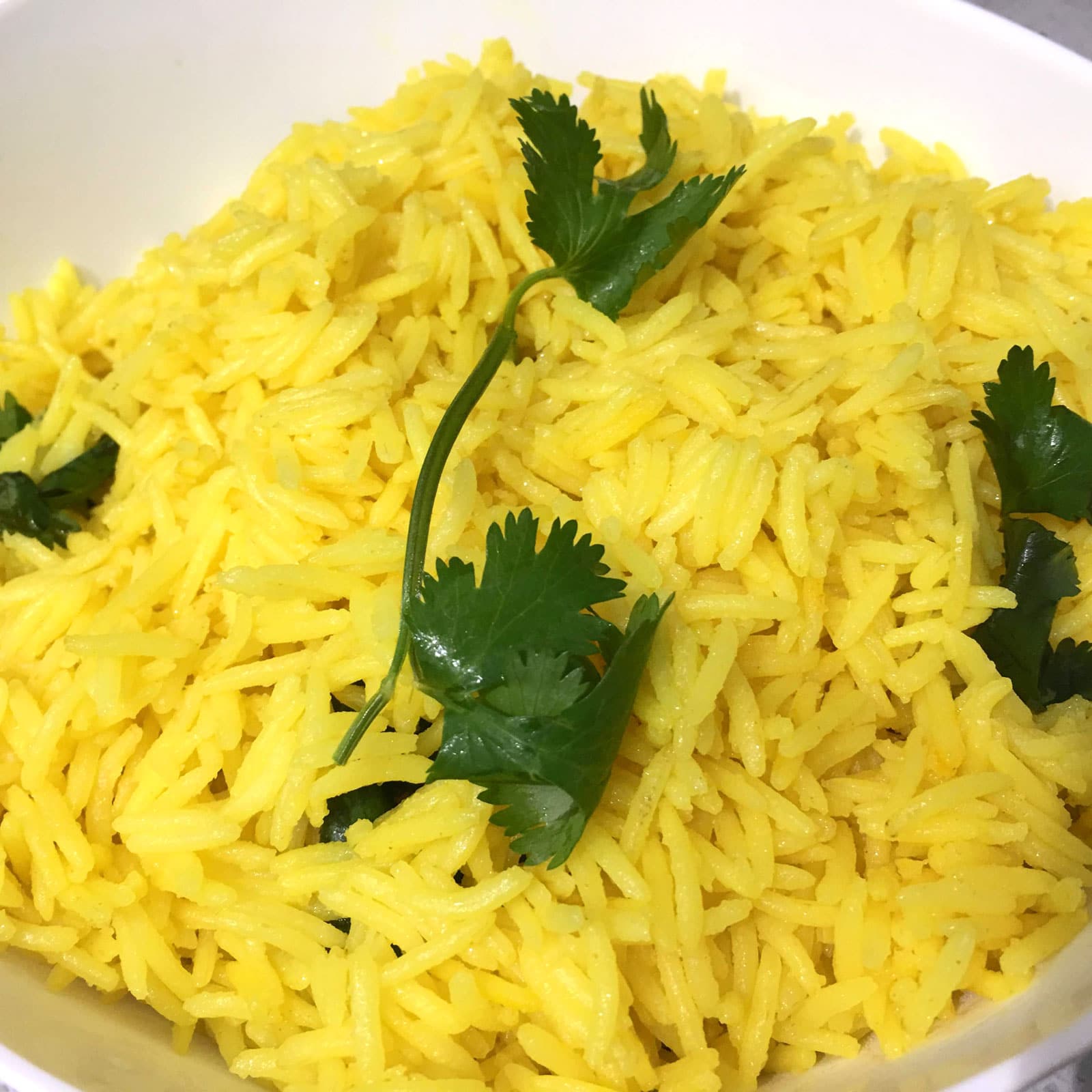 yellow rice garnished with cilantro leaves
