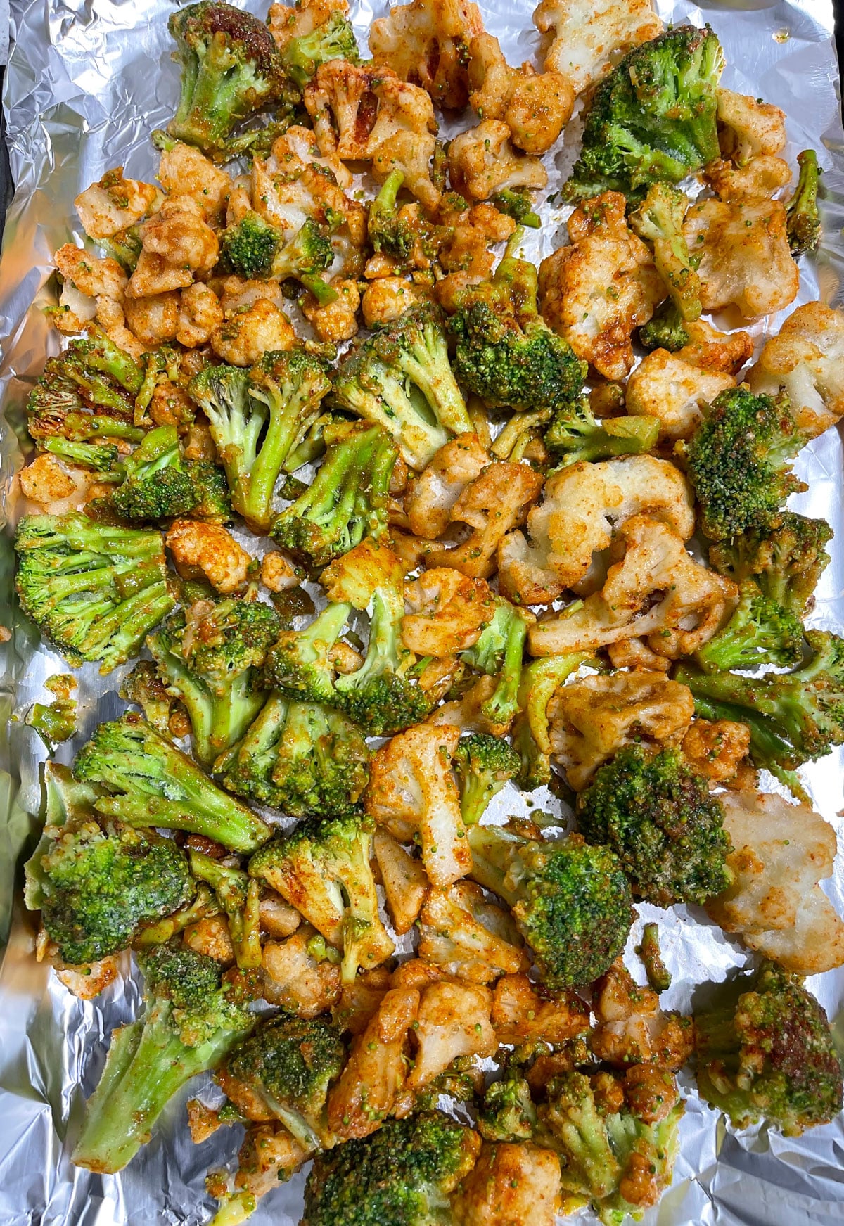 layer the seasoned broccoli and cauliflower in a baking sheet